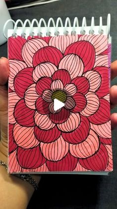 a hand holding a notebook with an image of a flower on it