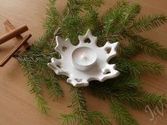 a white candle holder sitting on top of a wooden table next to some cinnamon sticks