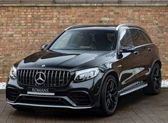 a black mercedes suv parked in front of a brick wall