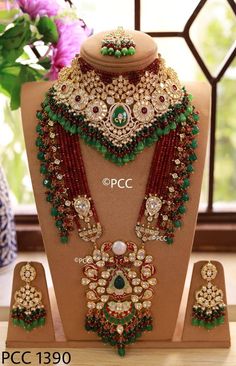 an elaborate necklace and earring set on display in front of a vase with flowers