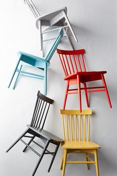 four different colored chairs against a white wall