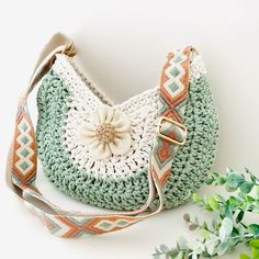 a crocheted purse sitting on top of a table next to a green plant