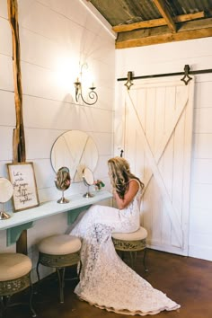 a woman sitting on a stool in front of a dressing table with mirror and stool