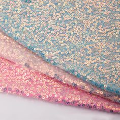 three different colors of sequinized fabric on top of each other, one pink and one blue