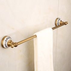 a gold towel rack with two white towels hanging from it's sides in a bathroom