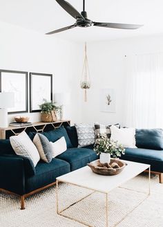 a living room with blue couches and white rugs on the floor in front of two windows