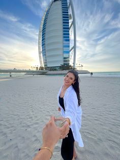 a woman is taking a photo with her phone on the beach in front of burj al arab hotel