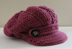 a crocheted hat with a button on the side sitting on a white surface