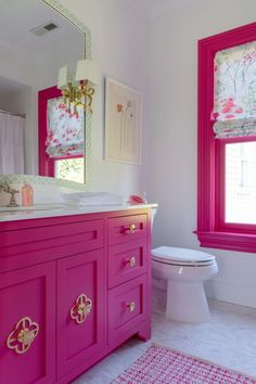 a bathroom with pink cabinets and white toilet