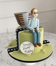 a cake with a man sitting on top of it and the words happy birthday written below