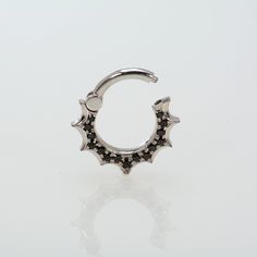 a silver nose ring with black stones on it's sides and a star design in the middle