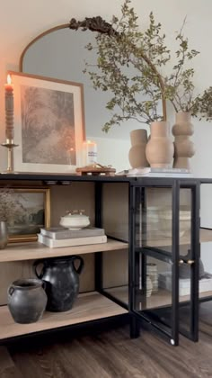 a table with vases, candles and pictures on it in front of a mirror