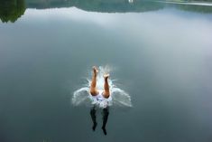 a person is swimming in the water with their arms up and legs spread wide out