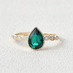 a gold ring with an emerald colored stone and diamond accents