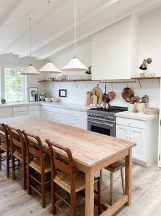 a large wooden table sitting in the middle of a kitchen next to a stove top oven