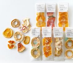 an assortment of fruits and snacks in plastic bags on a white surface, labeled with their names