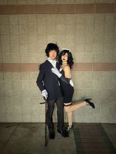 a man and woman dressed up in costumes posing for the camera with one holding a cane