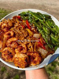 a person holding a plate of food with noodles and vegetables on it in their hand