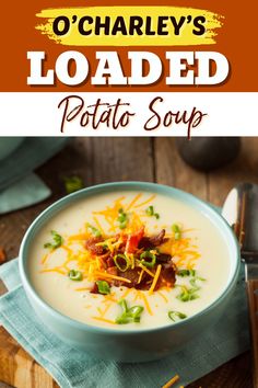 a bowl of loaded potato soup on top of a wooden table with cheese and bacon