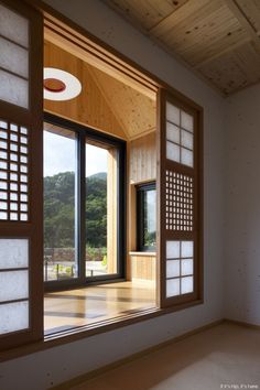 an empty room with large open windows and wood paneling