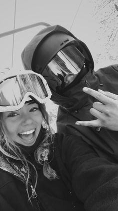 a man and woman posing for a photo while wearing ski goggles on their heads