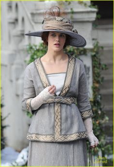 a woman in a dress and hat walking down the street