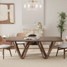 a dining room table with two chairs and a fireplace in the background, surrounded by art