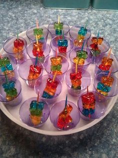 there are many gummy bears in cups on the plate with toothpicks sticking out of them