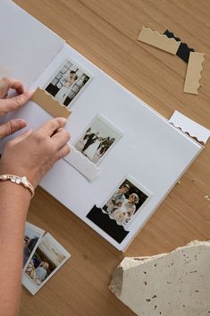 a person is making a photo album with photos on the table next to some paper