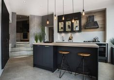 a kitchen with two bar stools next to an island and stairs in the background