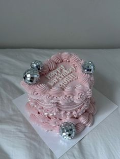 a pink birthday cake sitting on top of a white sheet