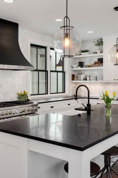 a large kitchen with an island in the middle and two pendant lights hanging from the ceiling