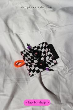 a black and white checkered bag with orange handles on top of a white sheet