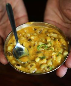 a person holding a metal bowl filled with food and a spoon in their hands,