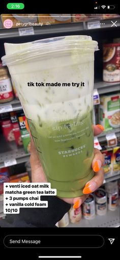 a person holding up a plastic cup filled with liquid in front of a store shelf