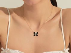 a woman wearing a necklace with a butterfly on it