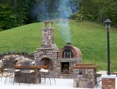 an outdoor stone pizza oven sitting on top of a patio next to a fire pit