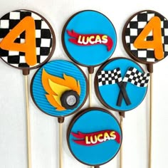 four cupcakes with racing cars on them are arranged in the shape of numbers