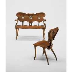 two miniature wooden chairs and a table with carved wood furniture on it's sides