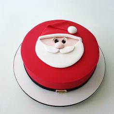 a red and white cake with a santa clause on it's face sitting on top of a plate