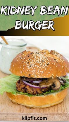 a burger with onions, mushrooms and lettuce sitting on a wooden cutting board