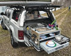 the back end of a white van with an open trunk and food trays in it