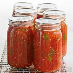 six jars filled with tomato sauce on a cooling rack