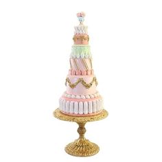 a three tiered cake sitting on top of a gold plated stand with pink, green and white icing