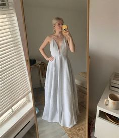 a woman taking a selfie in front of a mirror wearing a white wedding dress