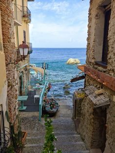 an alley way leading to the ocean with stairs going up and down it's sides