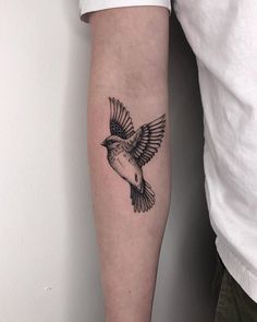 a small black and white bird tattoo on the arm