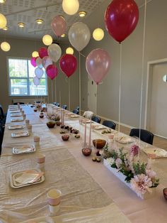 a long table with balloons and plates on it