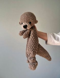 a crocheted teddy bear being held up by someone's hand in the air