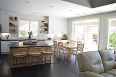 a living room and kitchen area with chairs, couches and an island in the middle